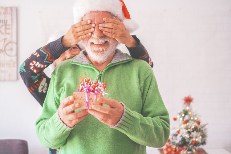 Woman covering eyes of man during christmas