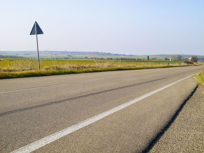 Road amidst field against clear sky