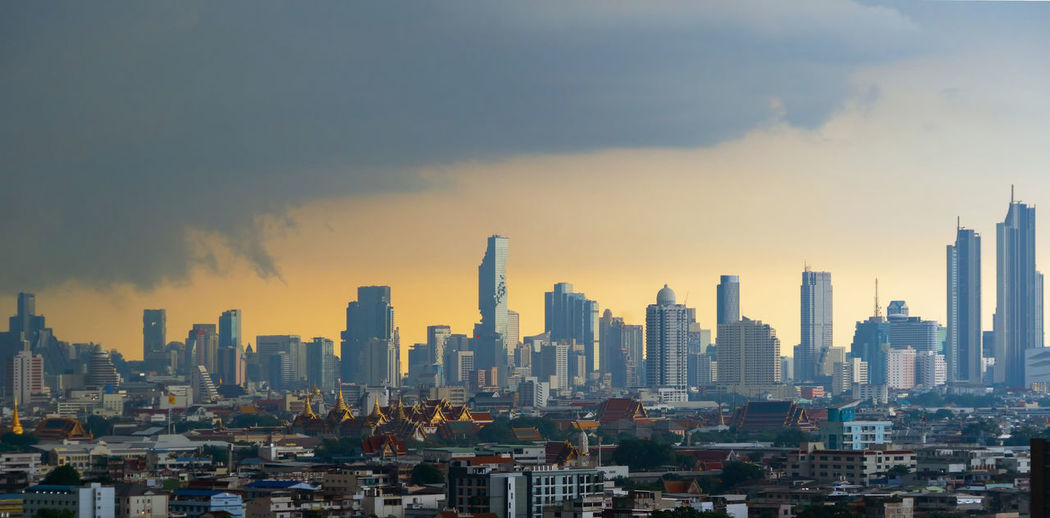 Modern buildings in city against sky during sunset