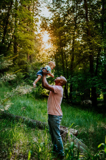 Vertical portrait of dad holding infant son up in the air