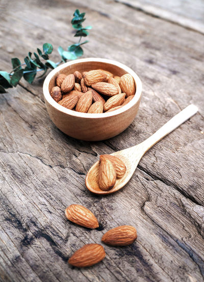 Almonds in a bowl against dark rustic wooden background