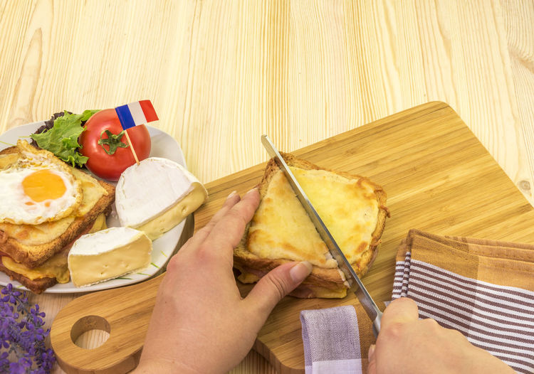 Woman cutting croque monsieur a traditional french sandwich