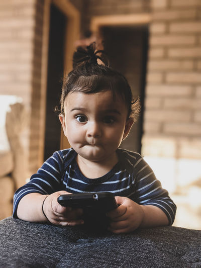 Portrait of cute boy holding smartphone /camera at home