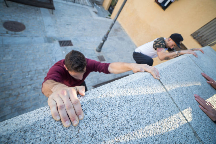 High angle view of male friends climbing wall