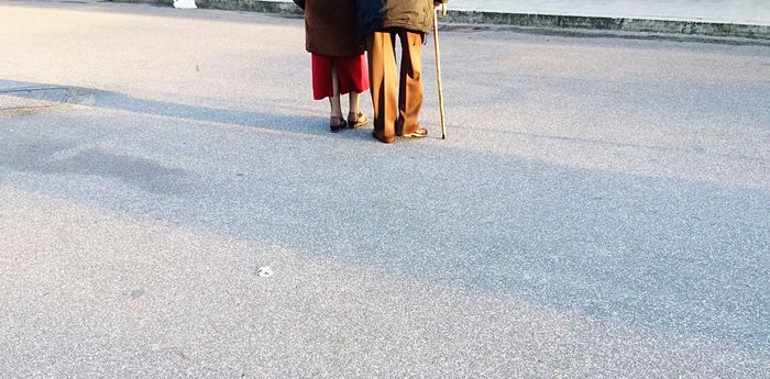 Low section of senior couple walking on street