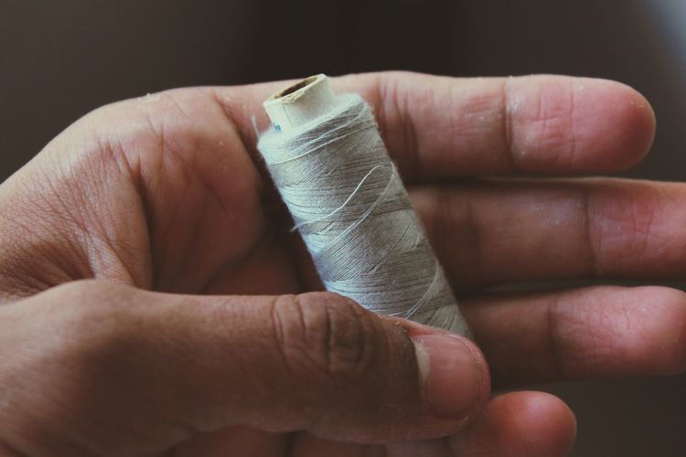 Close-up of hand holding thread spool