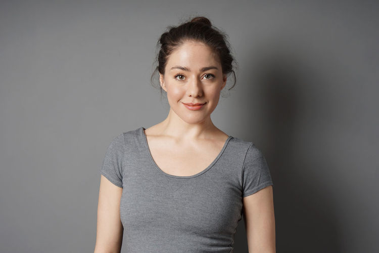Portrait of a smiling young woman against gray background