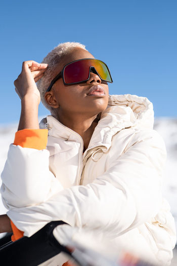 A young african american woman wearing sunglasses having fun in the snow on a winter day