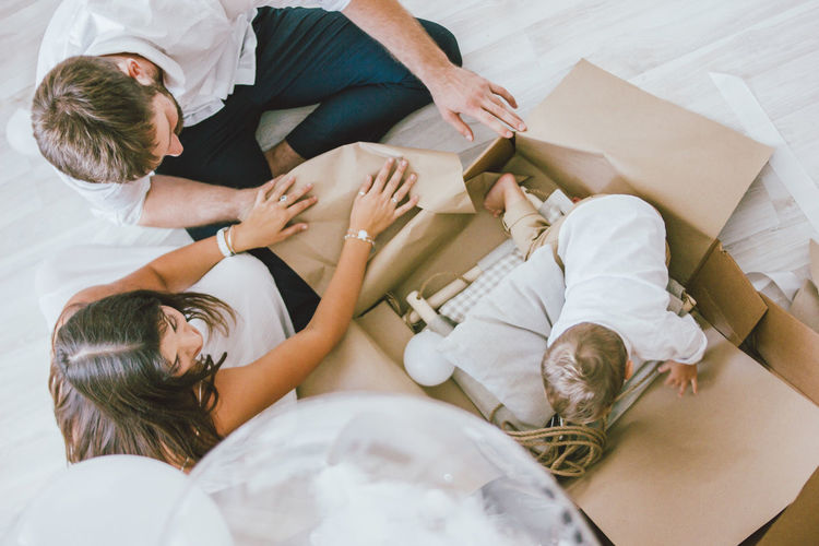 High angle view of son in box by parents sitting on floor at home