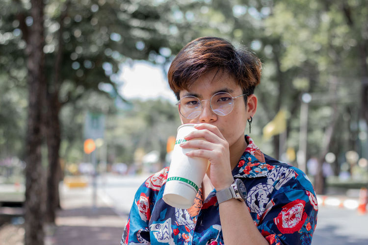 Portrait of man drinking coffee standing in park