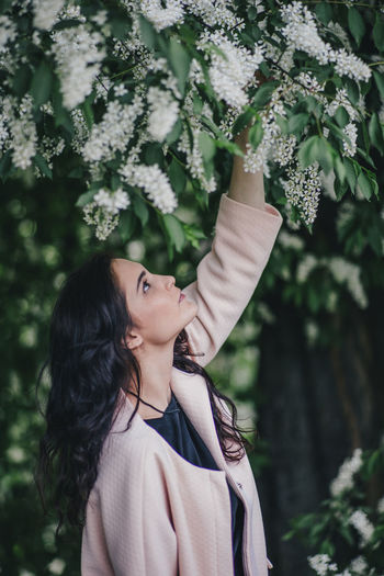 Portrait of young woman standing against plants