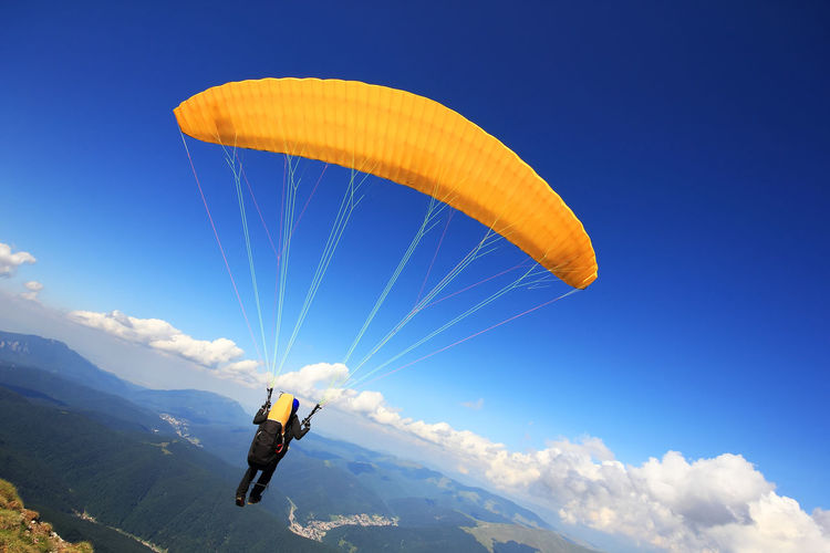 Rear view of one person paragliding over mountains