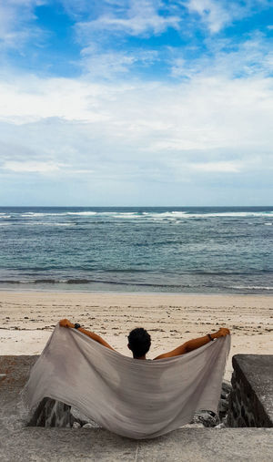 Rear view of man relaxing on beach
