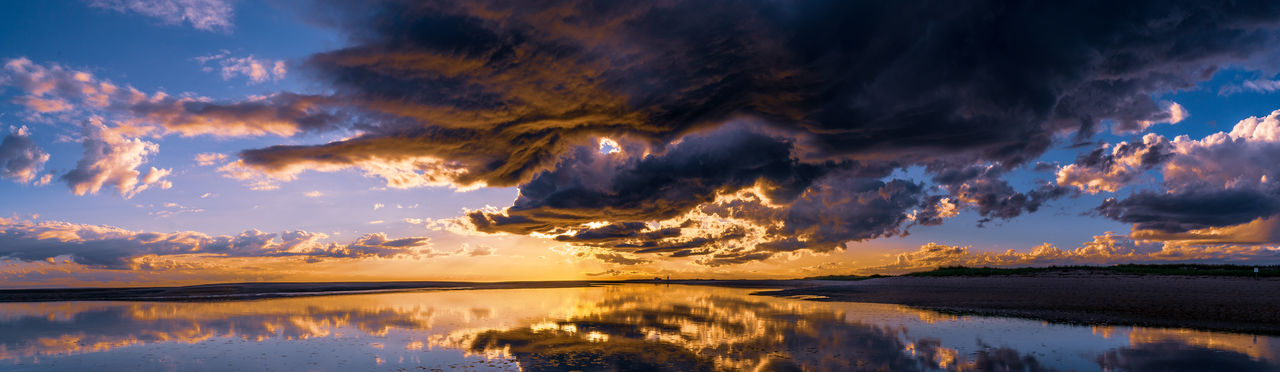 Panoramic view of lake against dramatic sky during sunset
