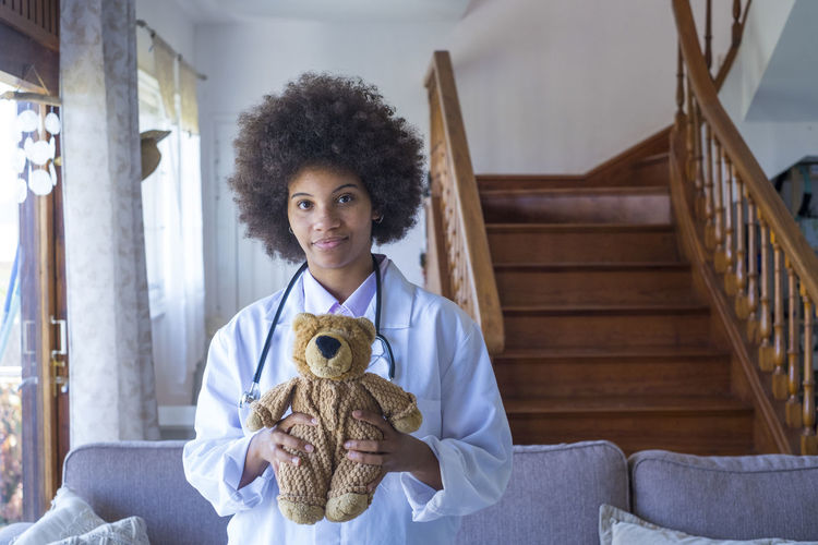 Portrait of doctor holding stuffed toy at home