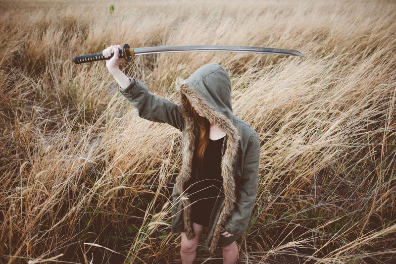 Woman holding sword while standing on field