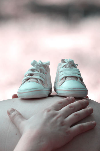 Midsection of pregnant woman with shoes on stomach