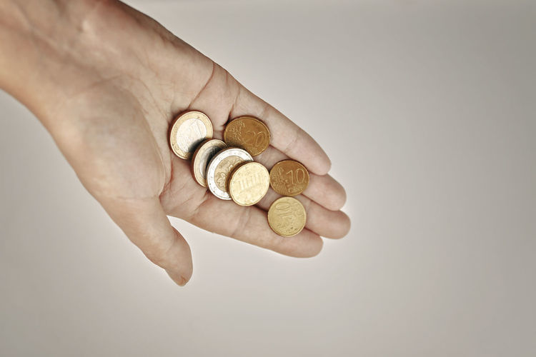 Close-up of hand holding coin against white background