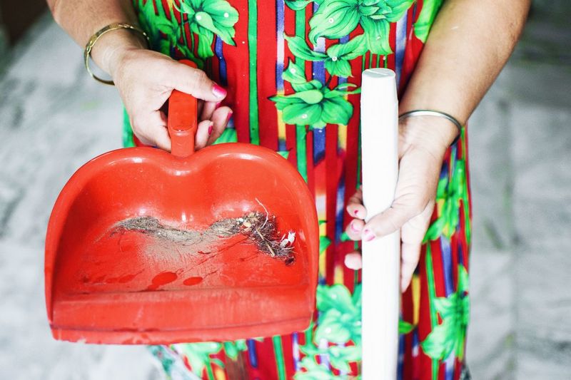 Midsection of woman with broom and dust pan standing at home