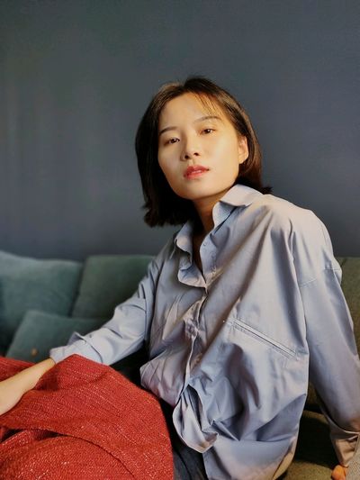 Portrait of young woman sitting on sofa at home