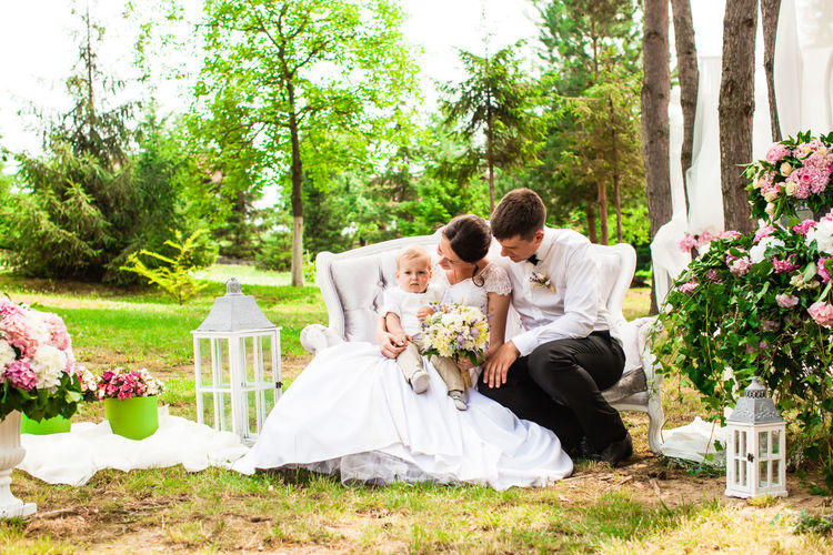 Rear view of bride and groom sitting in park