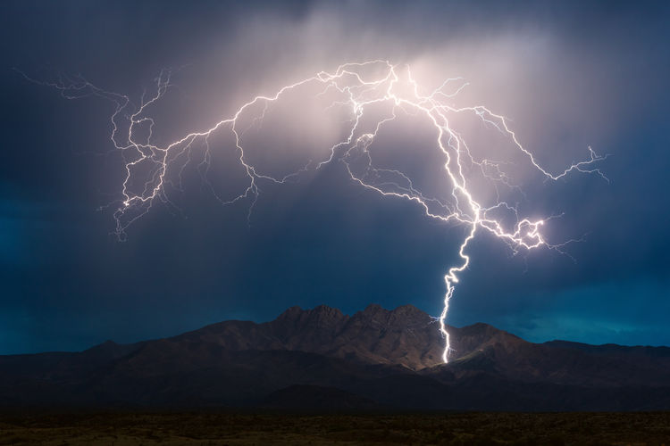 A lightning bolt strikes the four peaks mountain range during a monsoon thunderstorm in arizona