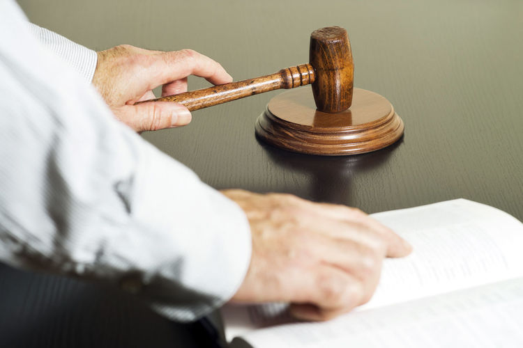 Cropped hand of lawyer holding gavel at table