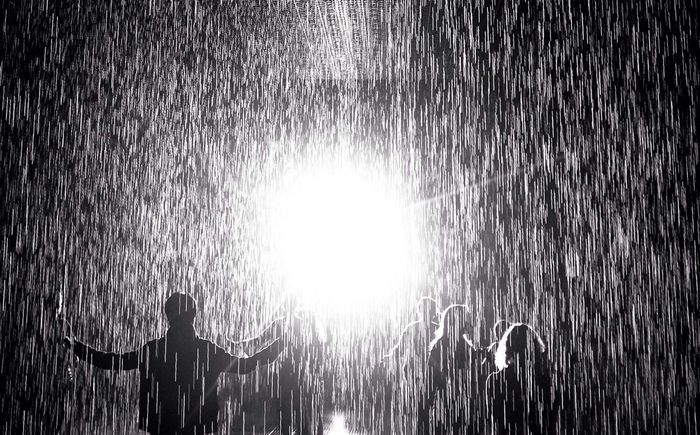 Group of silhouette people in rain against bright light