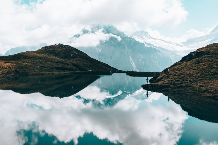 Panoramic view of calm lake surrounded by mountains against cloudy sky