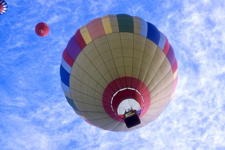 Low angle view of hot air balloons flying against cloudy sky