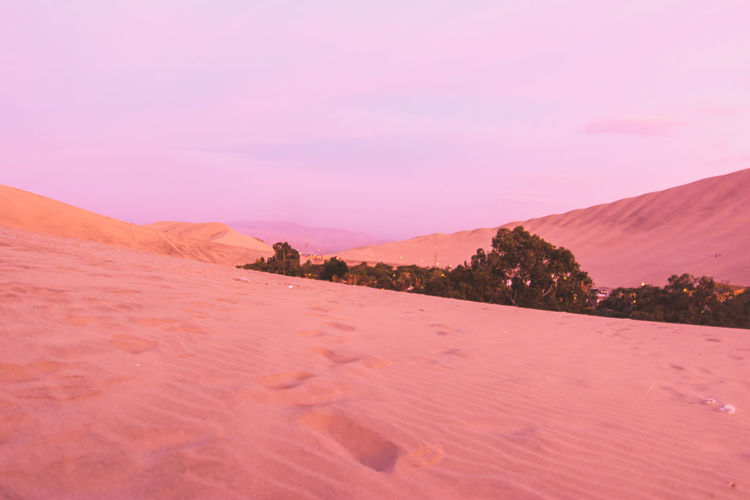 Sand dunes in desert against cloudy sky