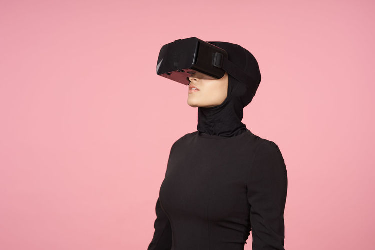 Low section of person wearing sunglasses standing against pink background
