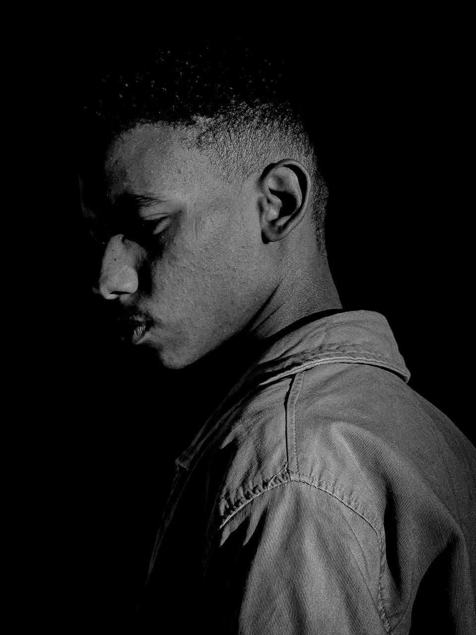 black and white, one person, black, darkness, black background, portrait, monochrome photography, monochrome, studio shot, headshot, adult, indoors, side view, men, looking, profile view, looking away, serious, copy space, dark, close-up, young adult, contemplation, lifestyles, person