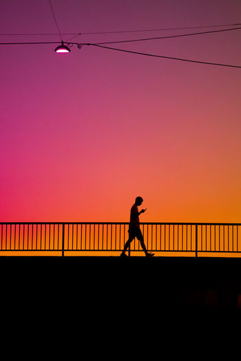 Silhouette man walking on pier against sky during sunset