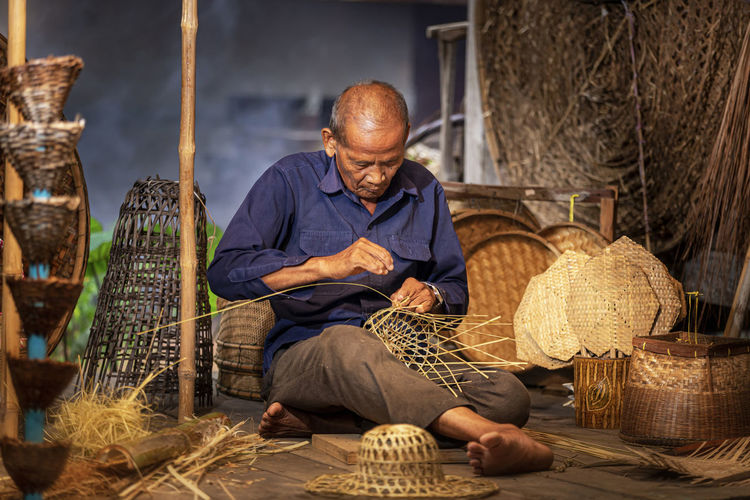 Man weaving basket at factory