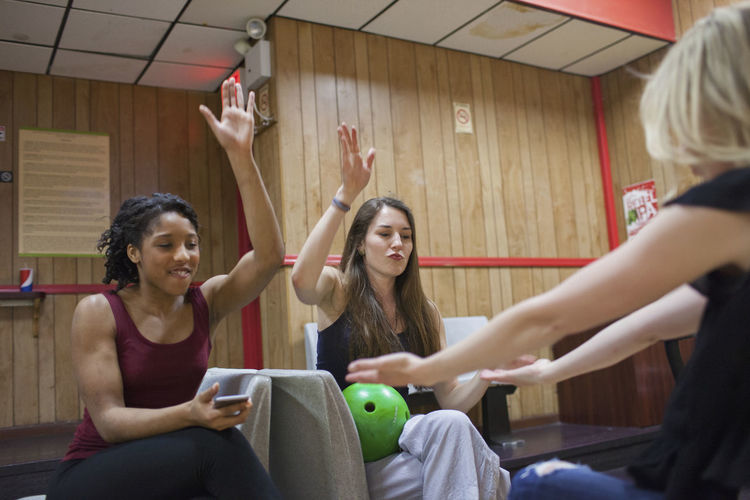 Three young women chereing at a bowling alley.