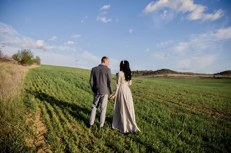 Rear view of couple on field against sky