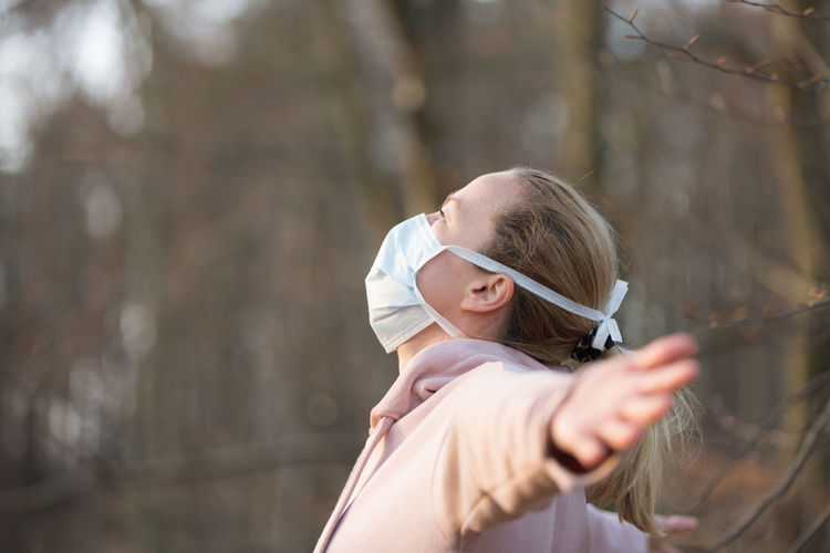 Side view of woman wearing mask standing outdoors