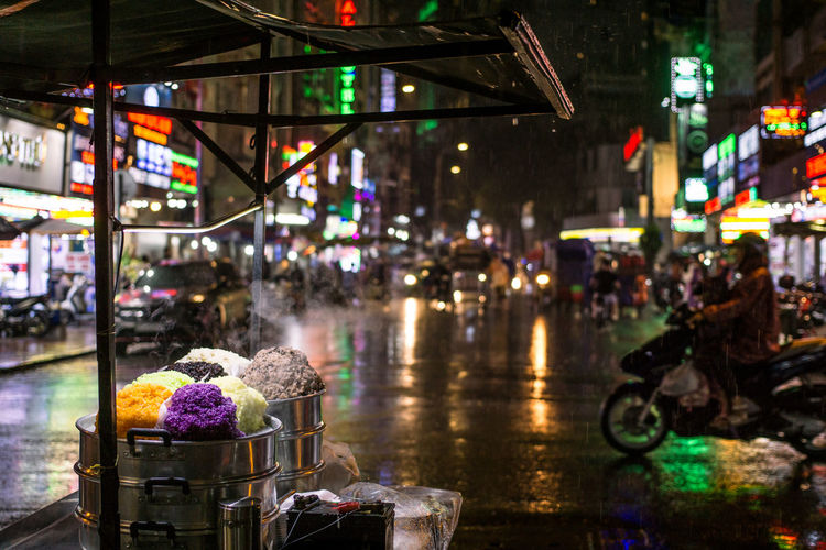Illuminated wet street in city during rainy season