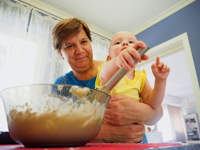 Low angle view of grandmother holding cute toddler in kitchen