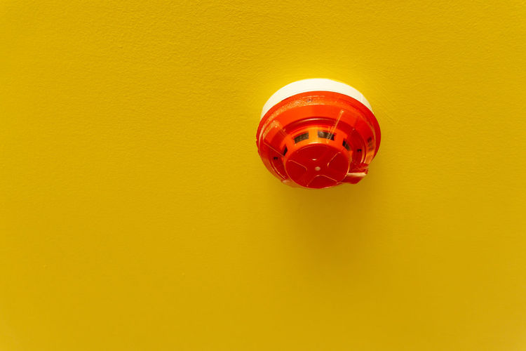 Red round smoke detectors provided on yellow ceiling background for security and fire alarm