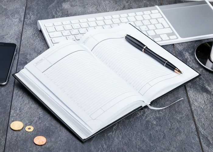 Close-up of pen and diary with keyboard