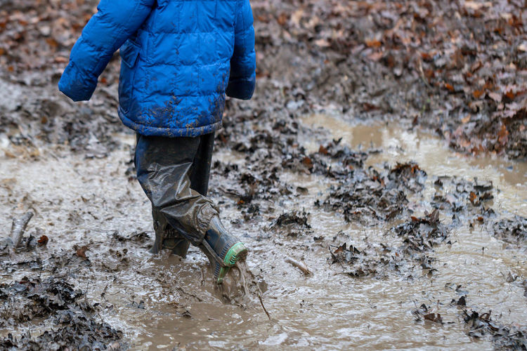 Low section of child walking in mud