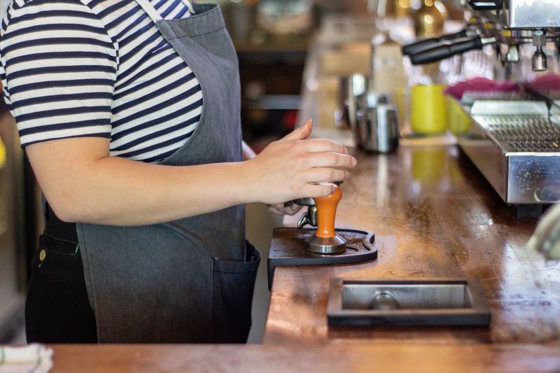 Midsection of barista preparing coffee in cafe