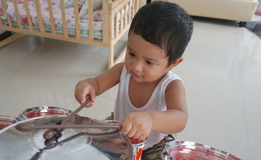 High angle view of cute baby boy playing drum kit at home