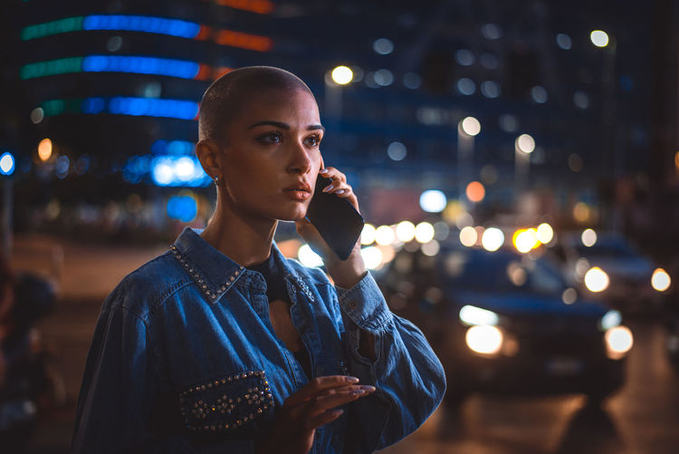 Portrait of young woman looking away in city at night