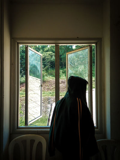 Rear view of man looking through window