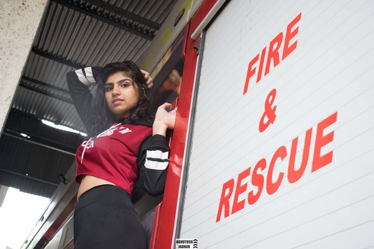 Portrait of young woman standing by fire engine outdoors