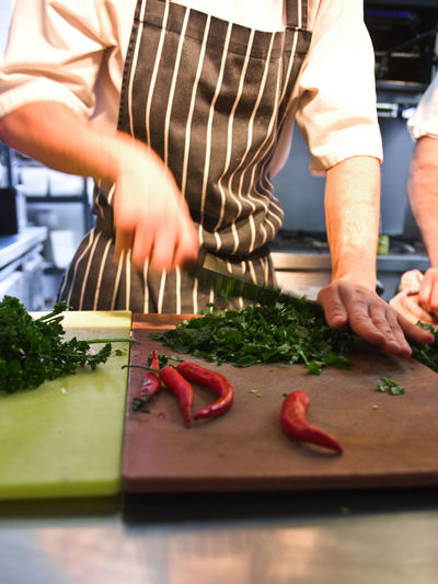 Chef chopping fresh herbs and chilli's at commercial kitchen
