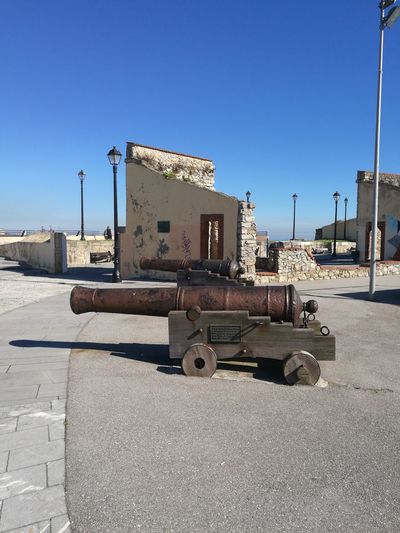 Old cannons on street against clear blue sky